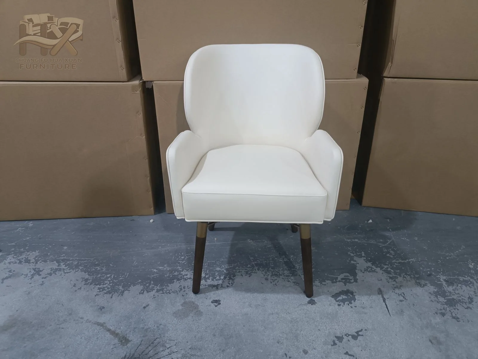 A white lounge chair lifts a softly winged back above one deep upholstered seat.