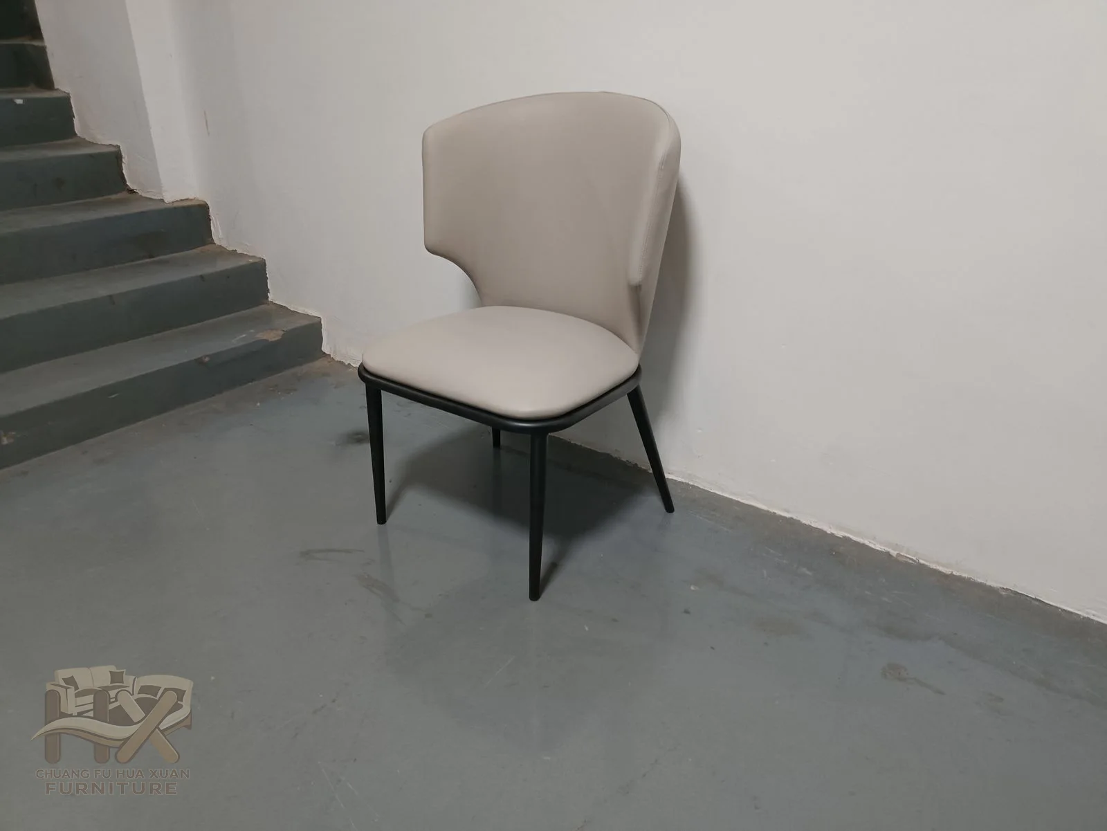 A soft shaped back narrows toward the seat, with dark slender legs providing contrast beneath the pale cover.