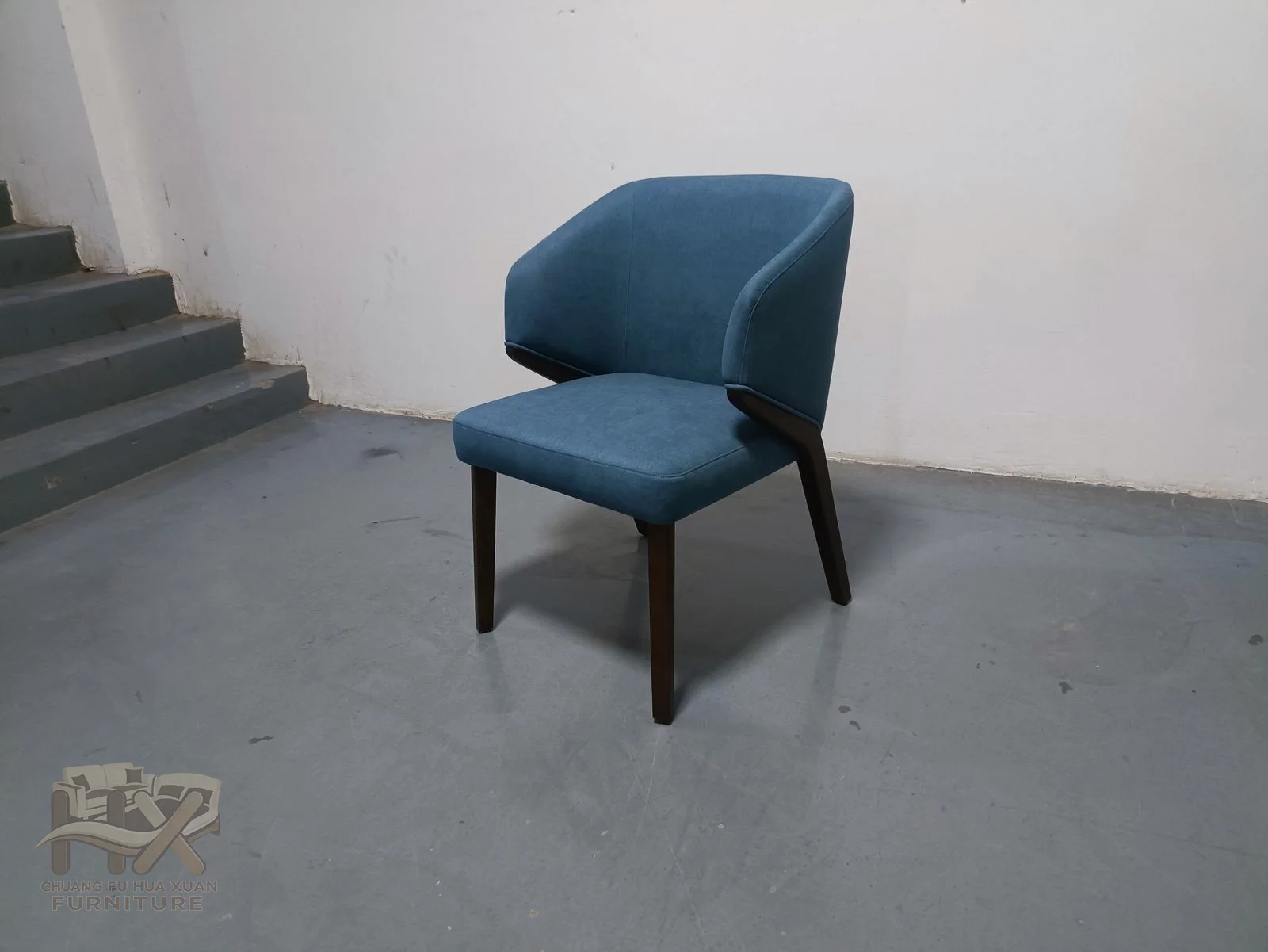 A smooth blue back curves down toward a compact upholstered seat above four tapered dark legs.