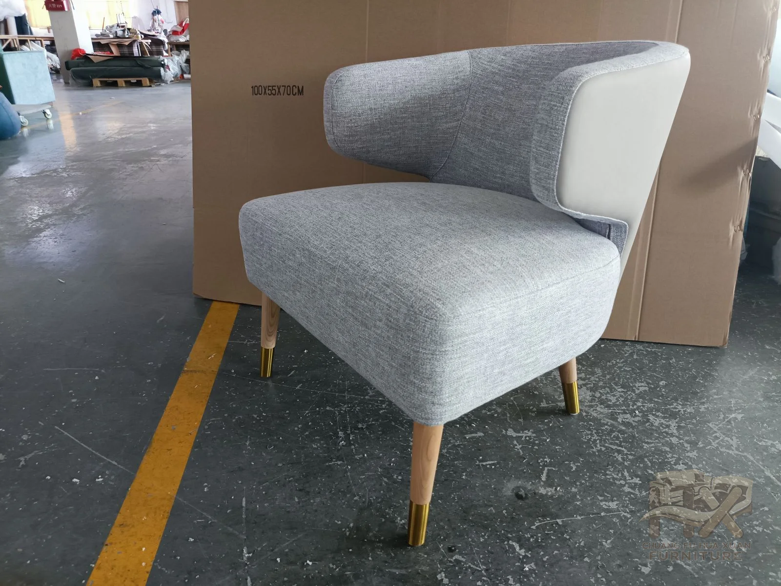 A grey upholstered back rounds into short arms above a slender open leg frame.