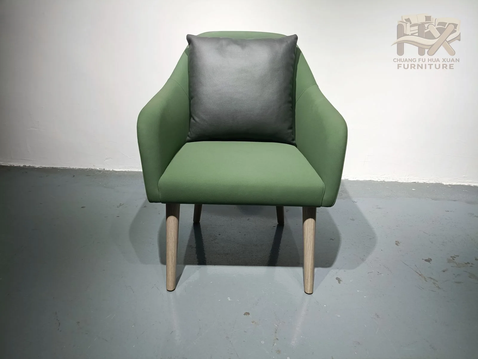 A green rounded seat sits inside a visible open arm frame with dark tapered legs.