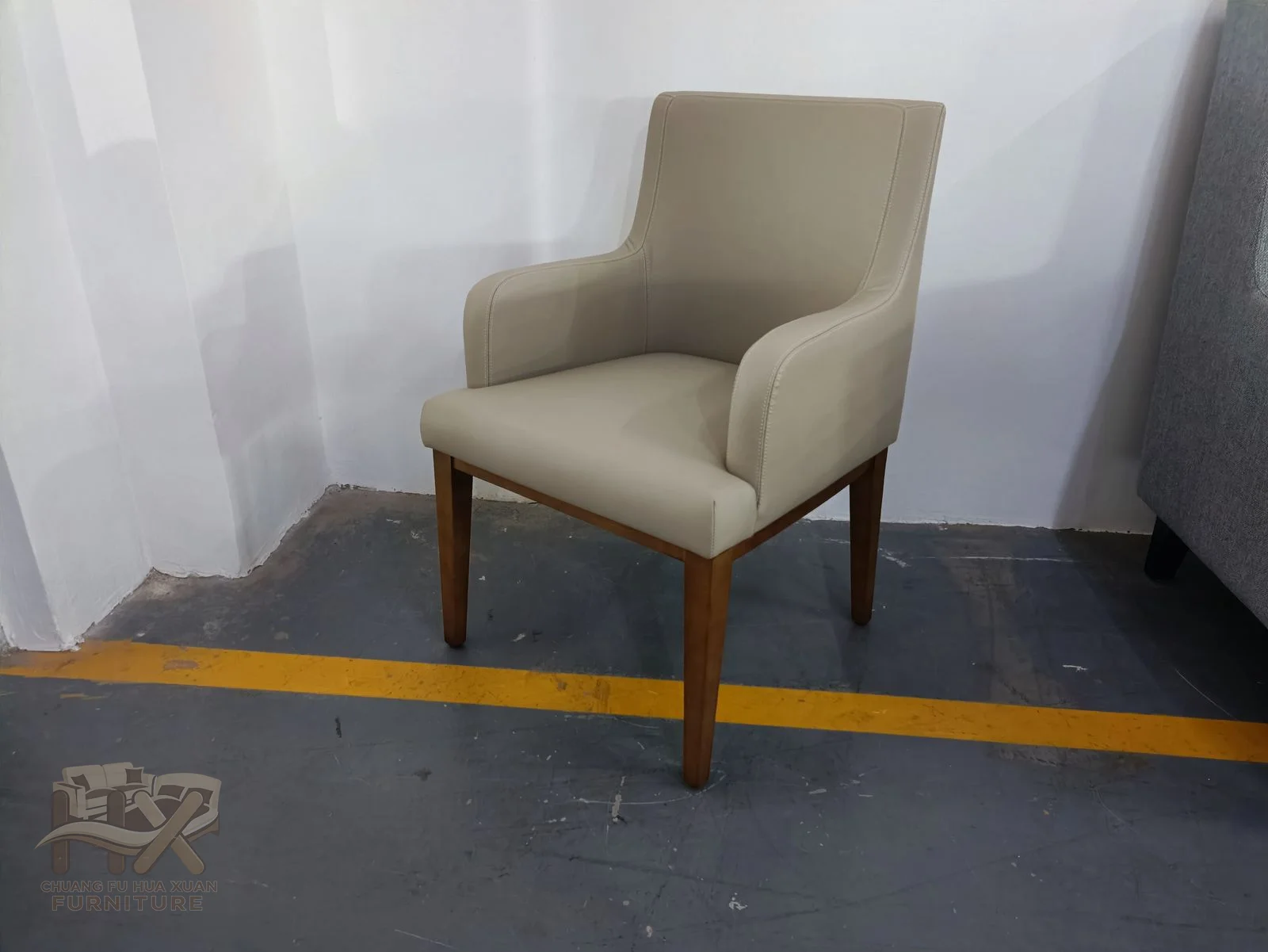 A soft pale back curves around short arms above four warm-toned tapered legs.