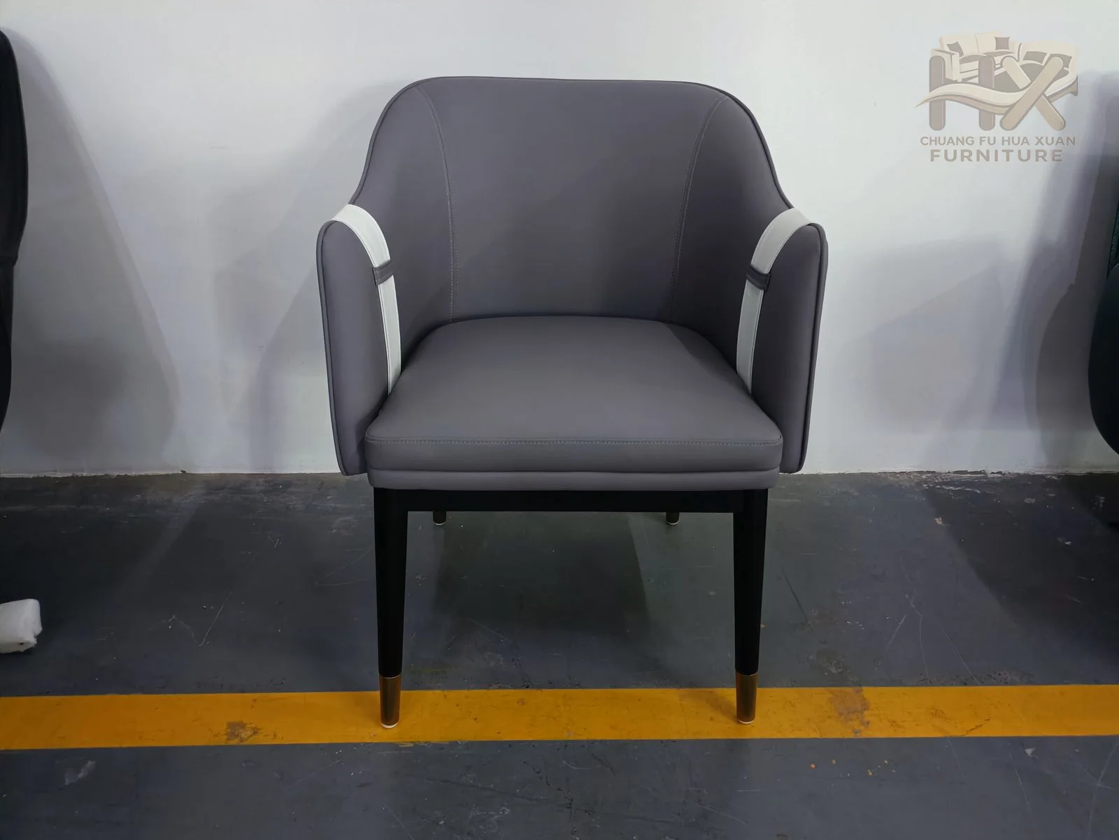 A grey upholstered seat meets a rounded back with a contrasting horizontal strap visible across the rear.