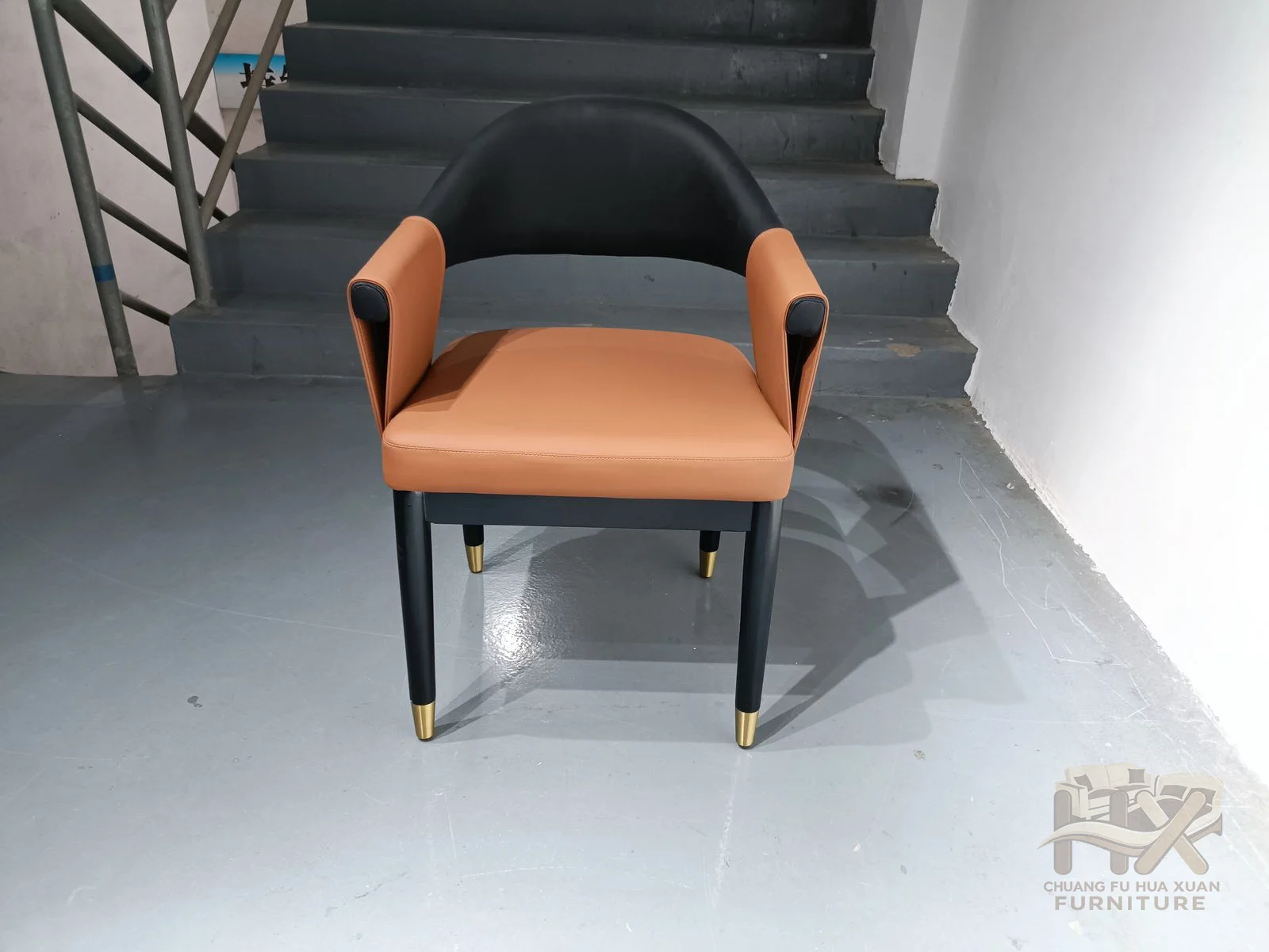 A warm tan inner seat contrasts with a dark curved outer back and slim four-leg frame.
