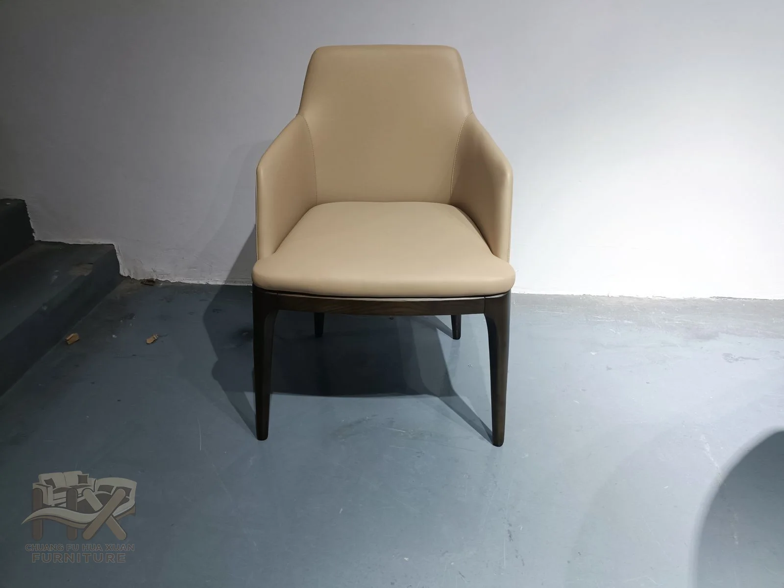 A sand-coloured upright back leads to short padded arms above dark narrow legs.
