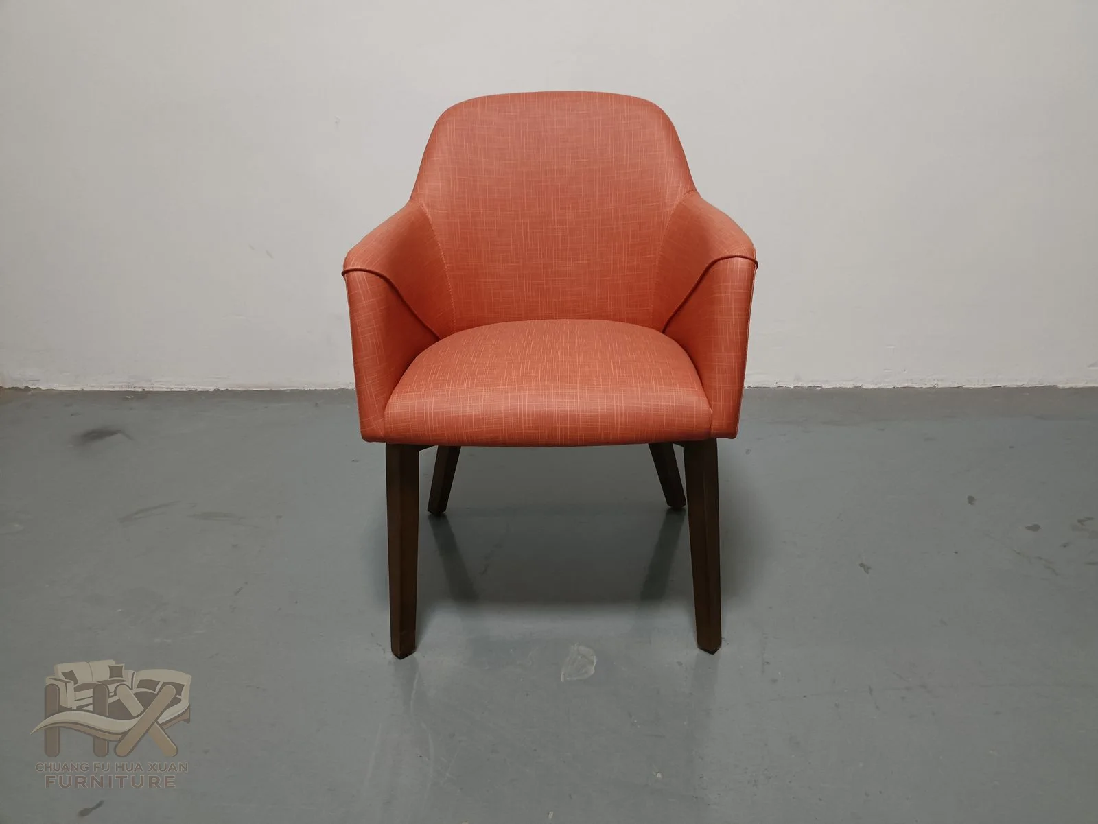 A terracotta upholstered shell curves into short open arms over tapered dark legs.