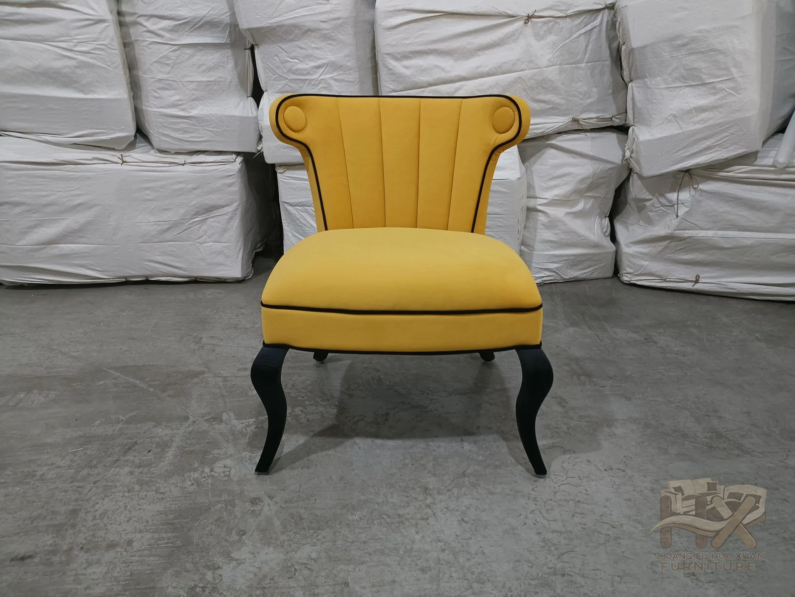 A tall yellow back and short upholstered arms frame a compact seat above dark tapered legs.