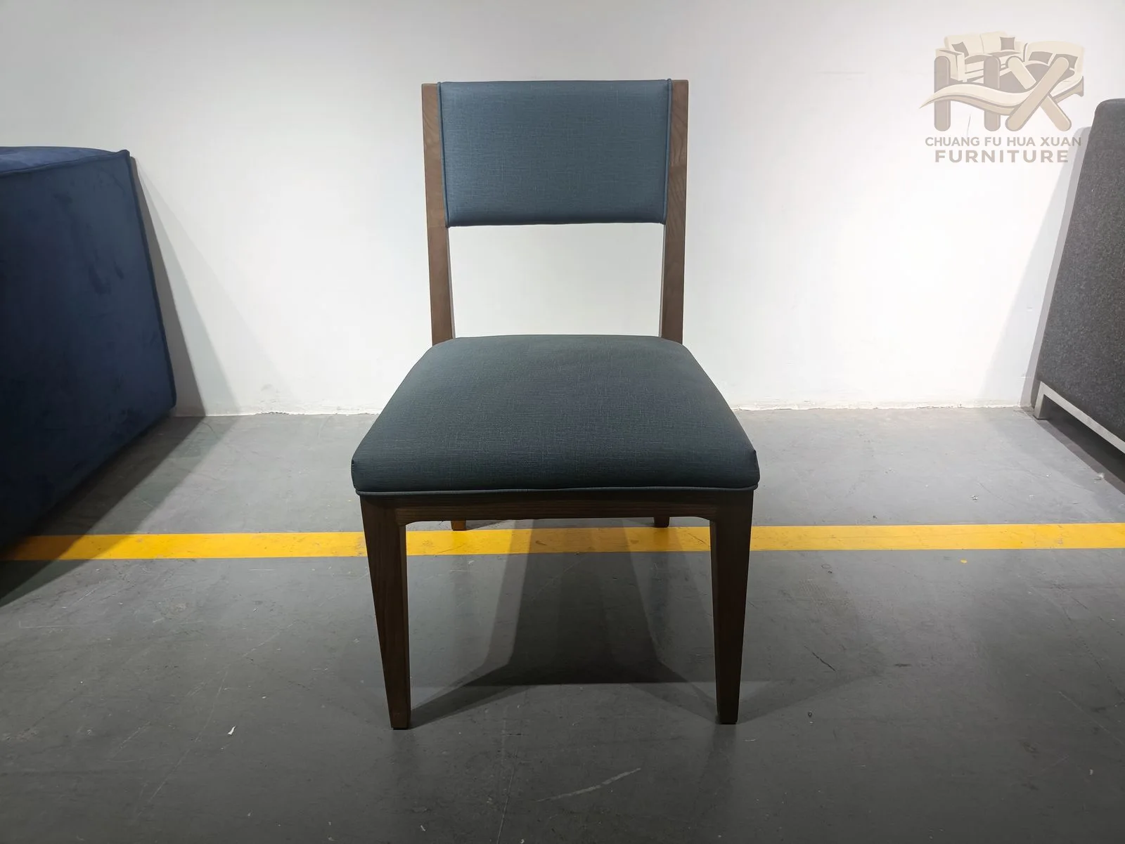 A small padded dining chair places a curved back over four dark tapered legs.