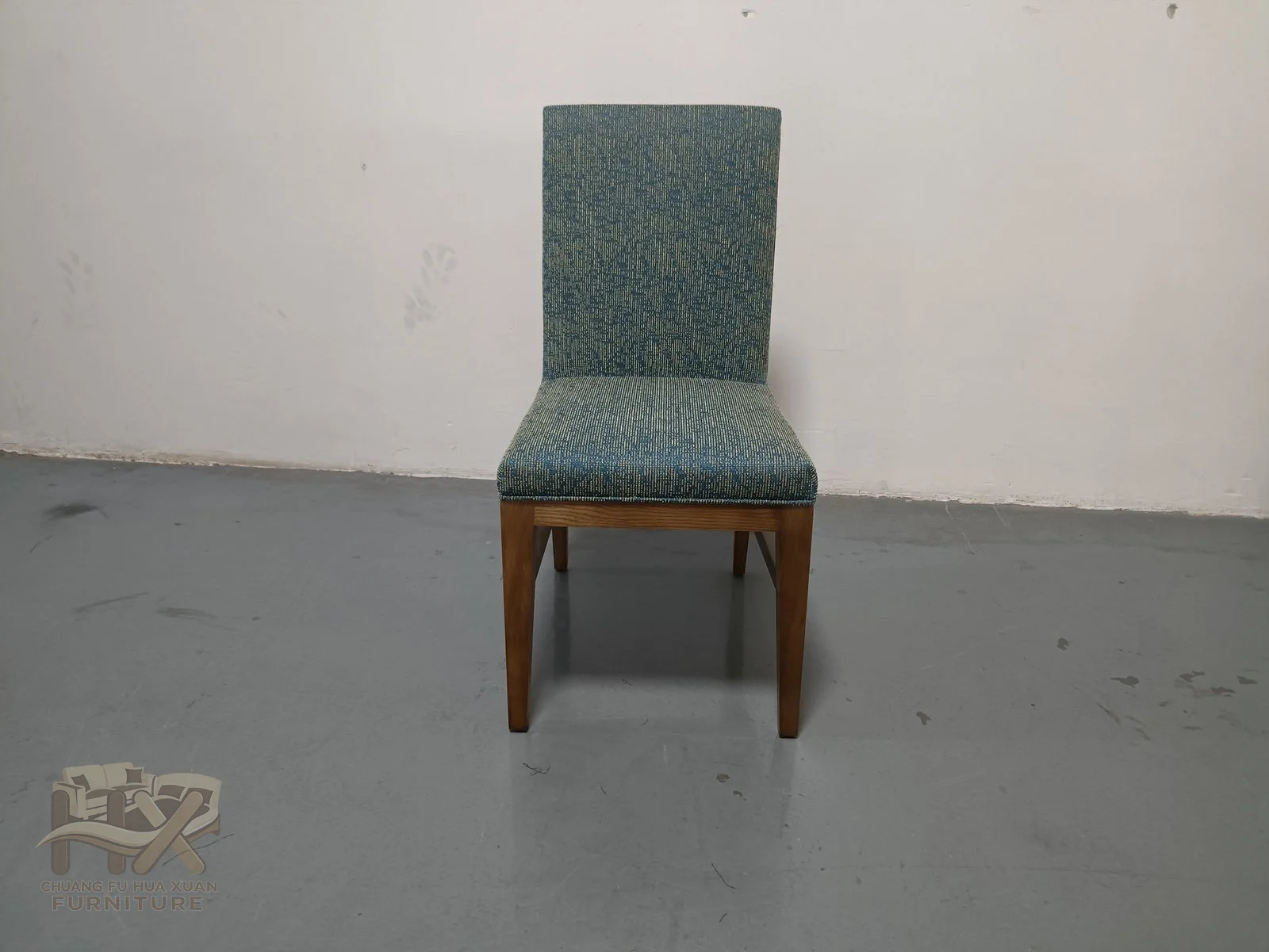 A teal dining chair has a narrow tall back above a padded seat on wood-look legs.