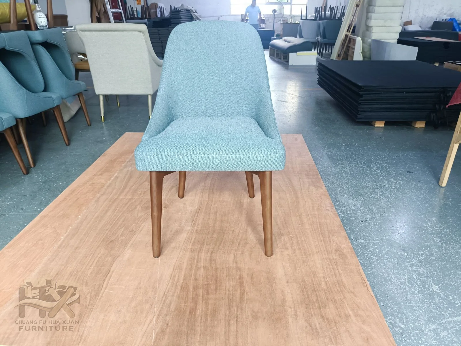 A light blue padded dining shell sits above four pale wood-look legs.