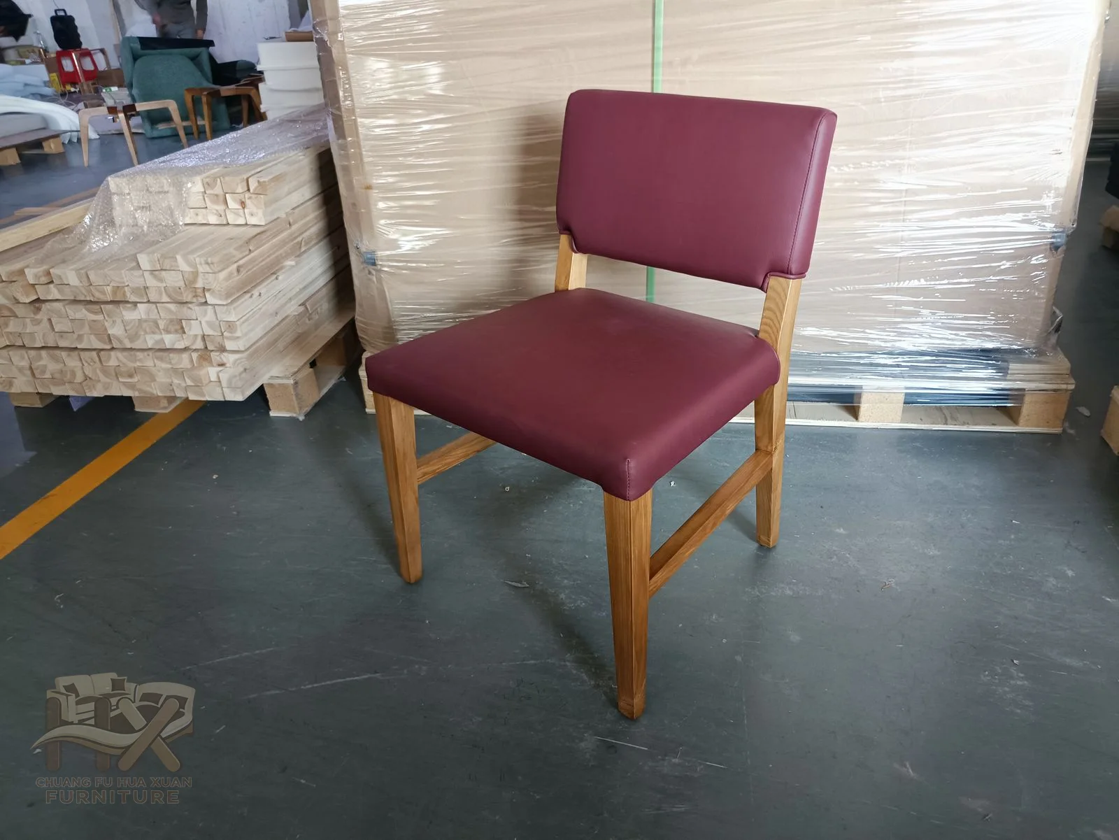 A burgundy padded dining seat and upright back stand on warm wood-look legs.