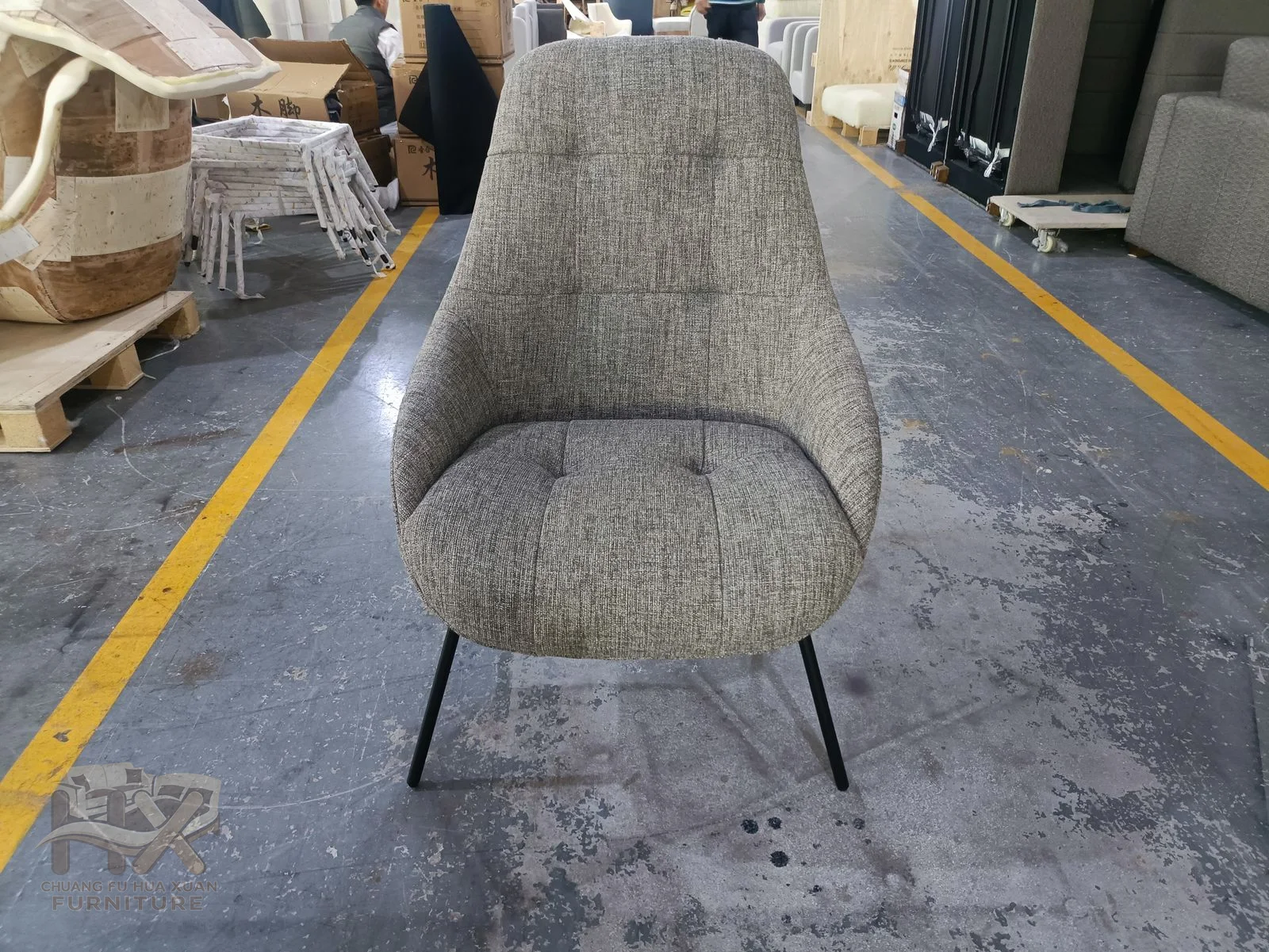 A grey upholstered chair inclines its broad back above fine dark legs.