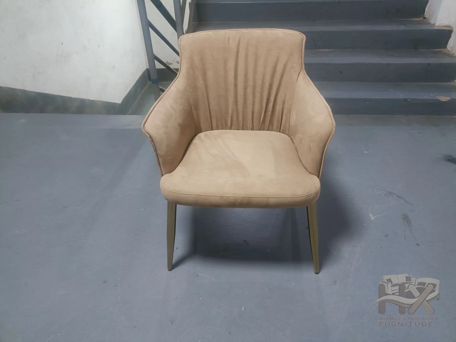 A sand-coloured chair fans narrow upholstered seams across its curved back.