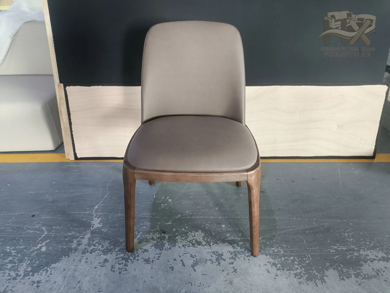 A taupe padded dining chair curves its back around a narrow seat on slim legs.