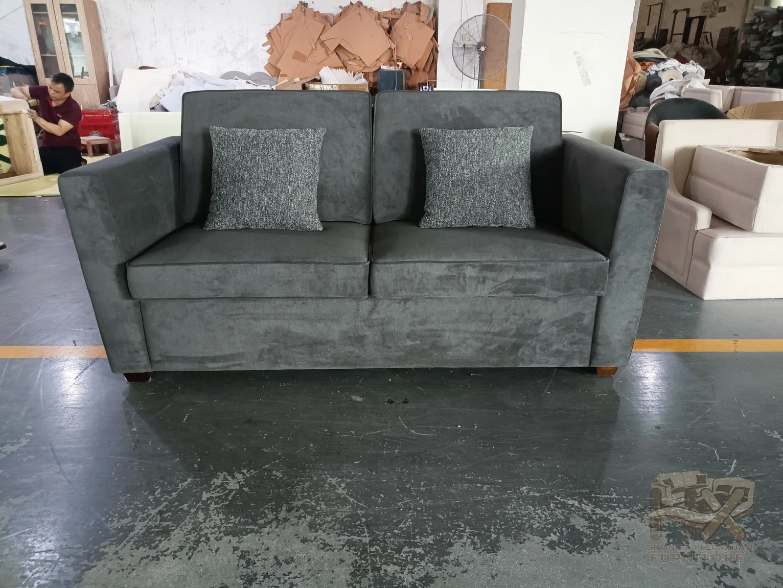 A grey sofa with level arms opens into a forward mattress platform while its back cushions remain upright.