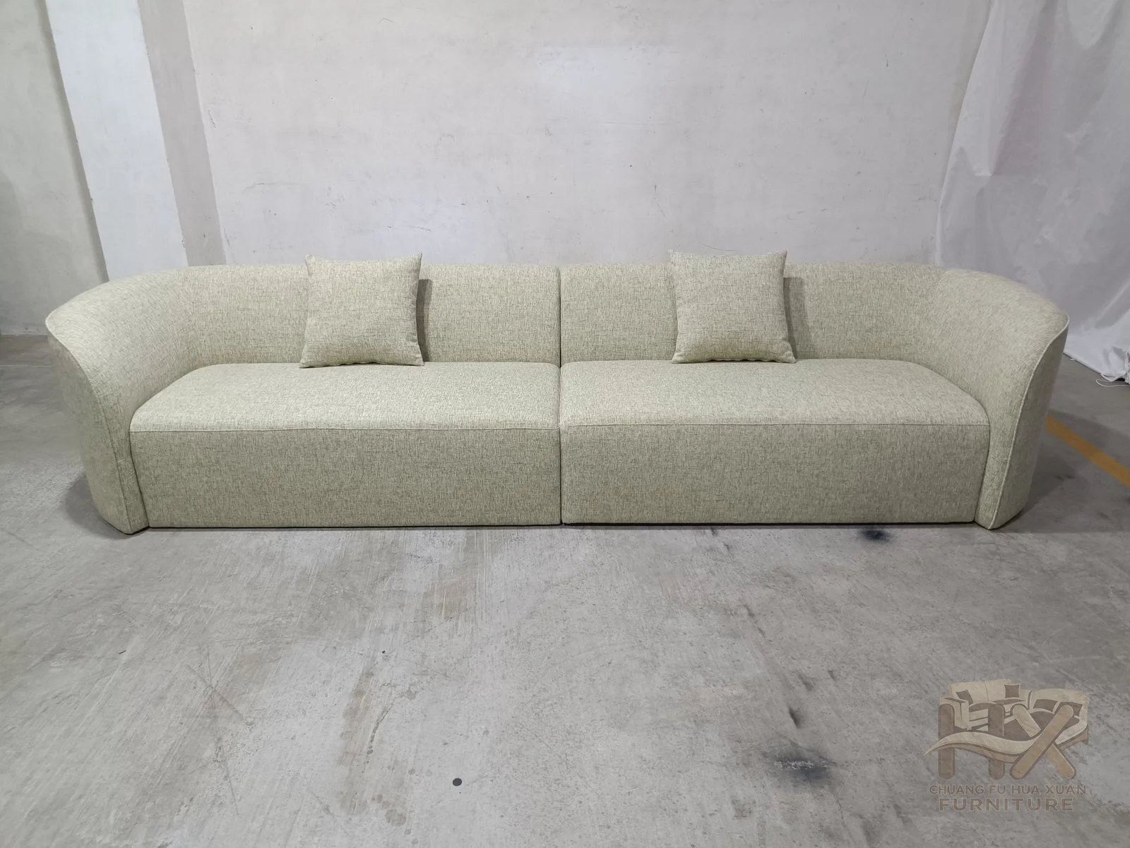 A long three-cushion seat meets broad rounded arms and a low, clean back without buttoning or exposed frame details.
