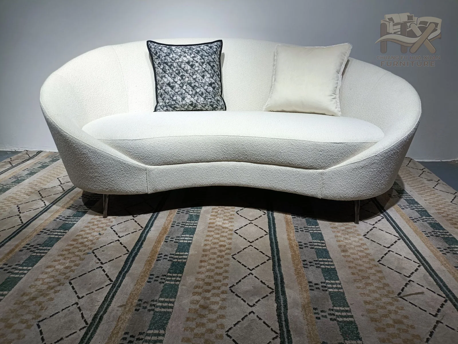 A short white sofa sweeps into curved ends, with slim loose cushions sitting inside its rounded back.