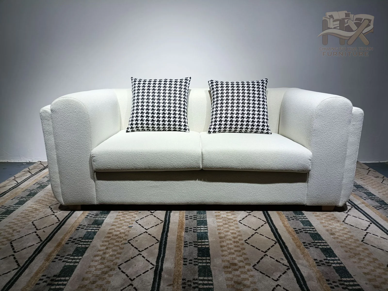 The sofa has broad arms that flare outward from a narrow base, with two seat positions and patterned cushions against a low back.
