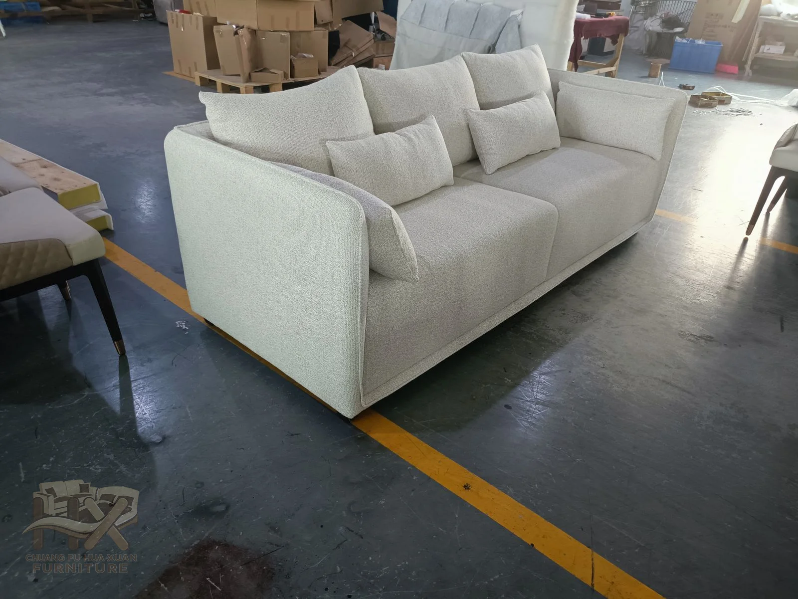 Three broad white seats and loose back cushions are held by level square arms and a straight upholstered frame.