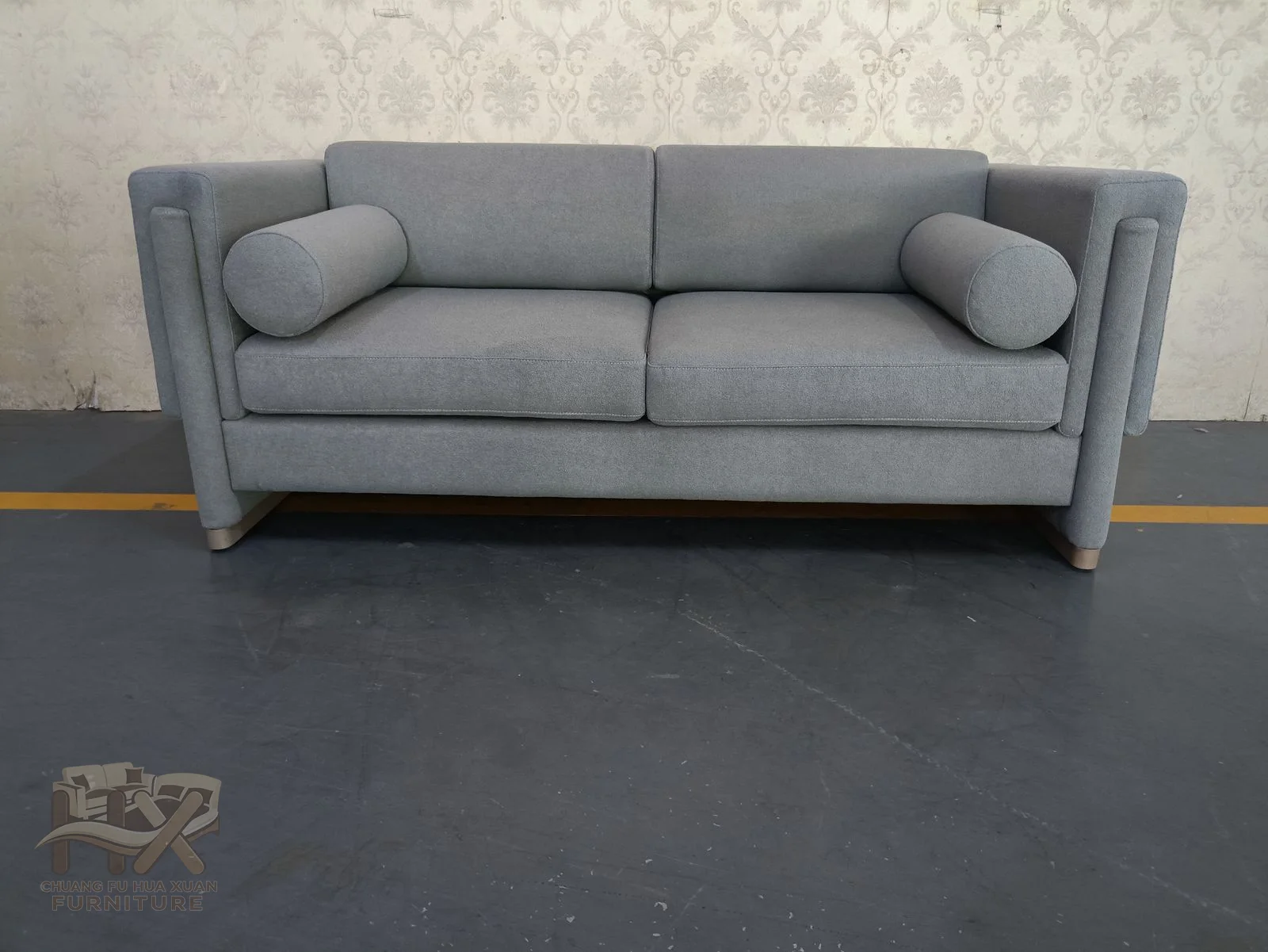 The grey sofa has pronounced rounded arms, two loose seat cushions and a straight cushioned back.