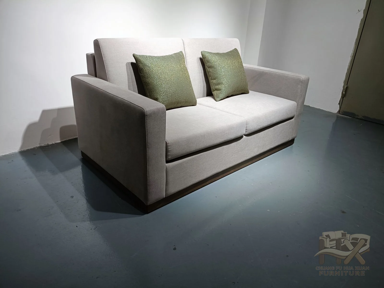A pale two-seat sofa uses straight narrow arms, an upholstered base and loose back cushions.