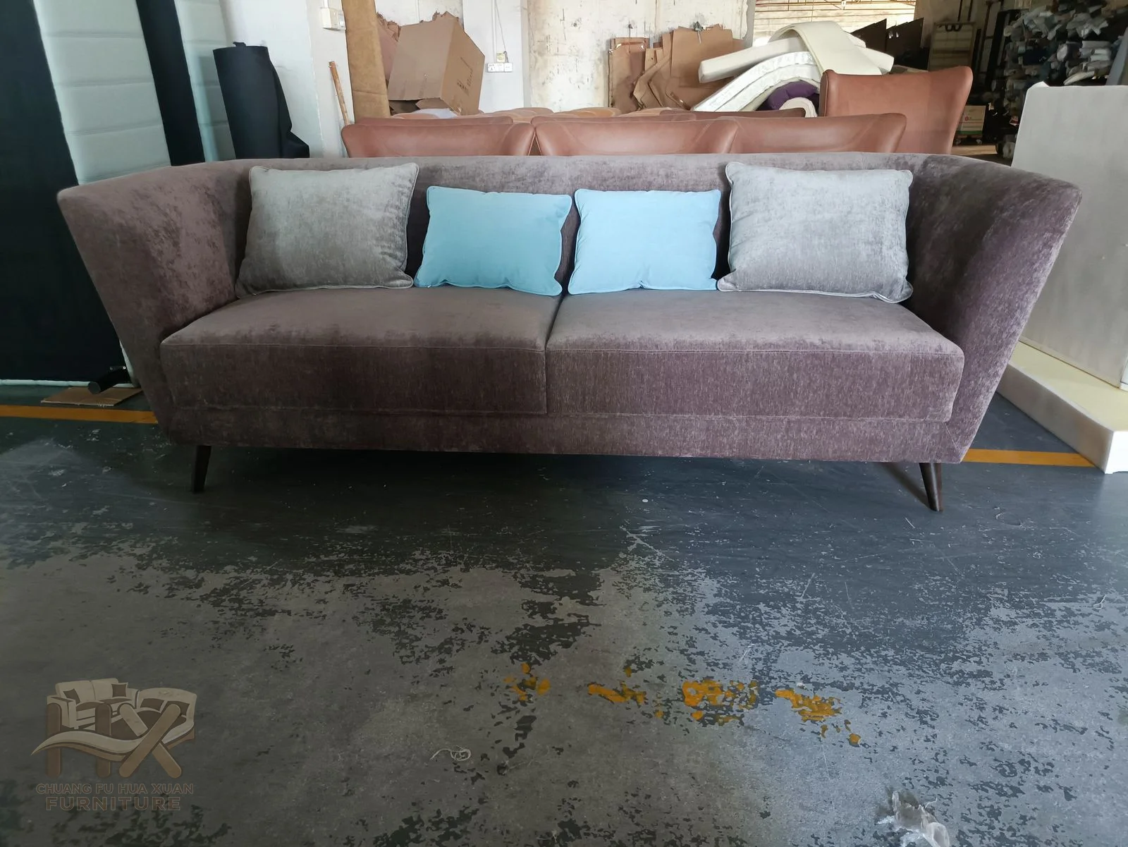 A low straight sofa uses softly rounded arms, deep loose seat cushions and pale back pillows in closely related mauve covers.