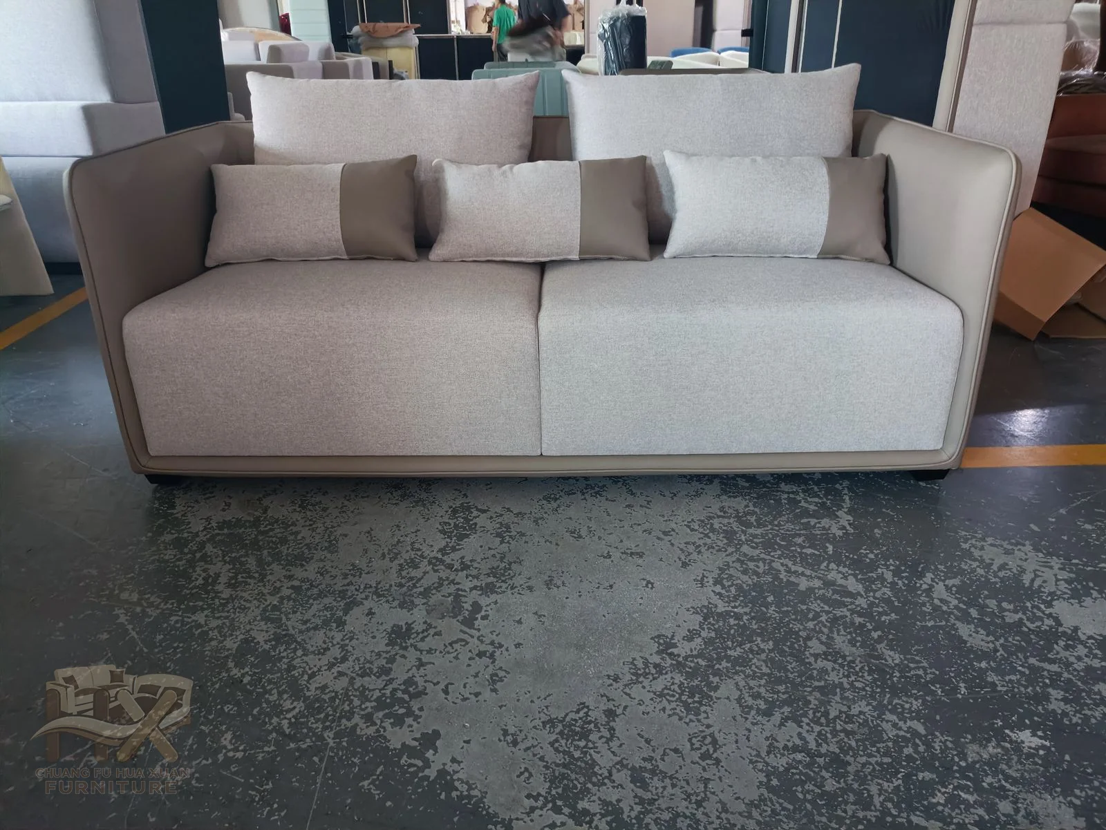 Tall narrow arms frame pale loose back cushions above a low ivory seat and slim dark feet.