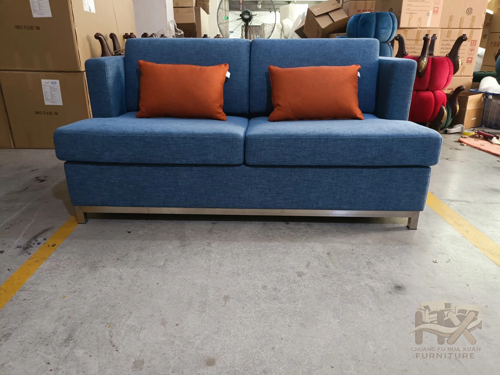 Blue loose cushions and orange accents sit between straight square arms over a compact upholstered base.