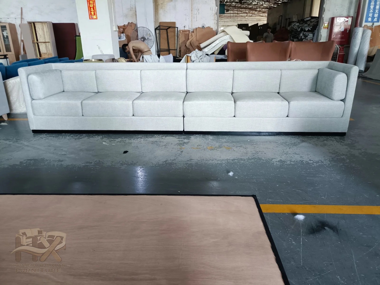 A long white seat continues between level box arms with a repeated row of soft back cushions.