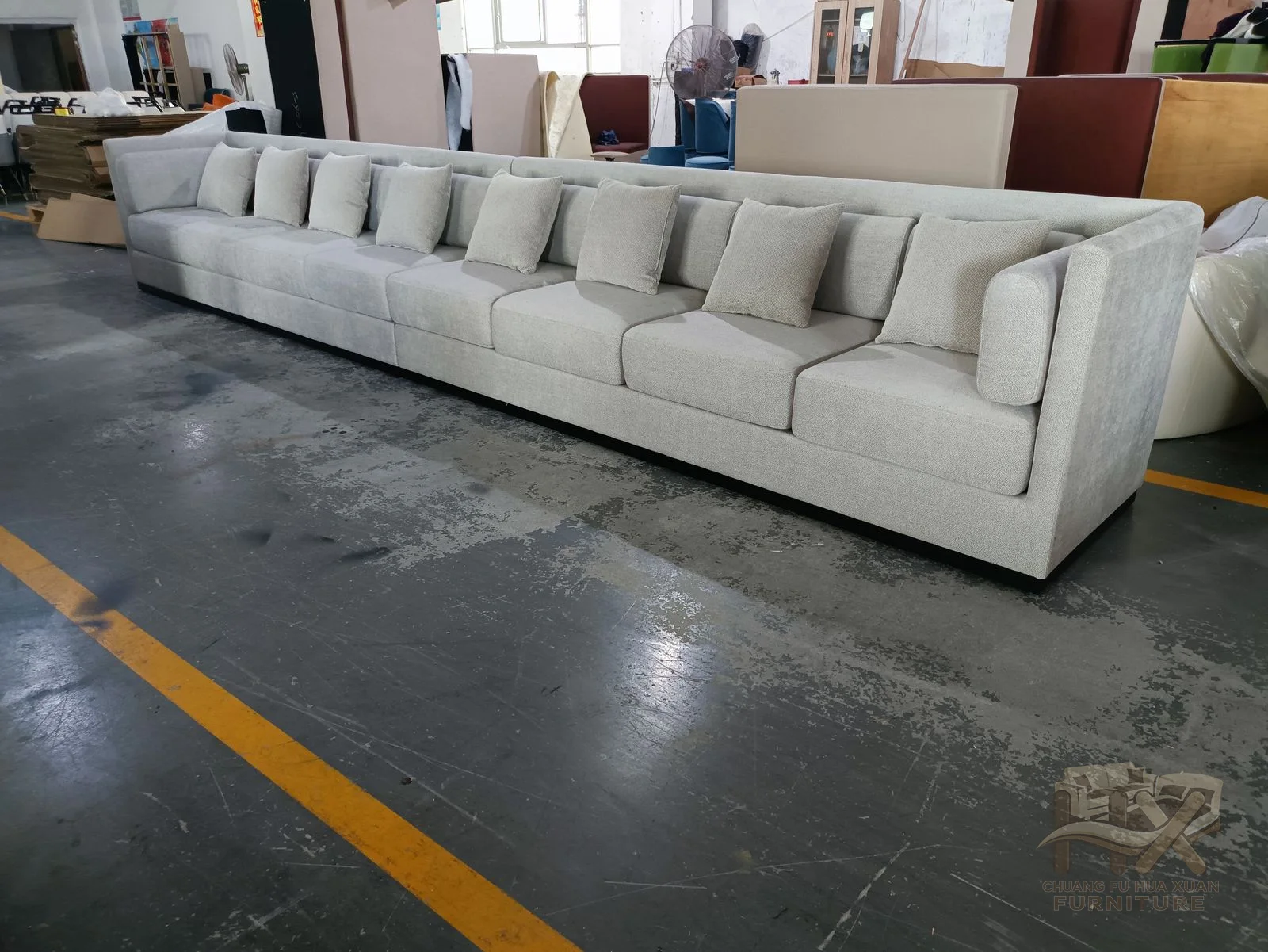 A broad white sectional combines deep seats and a low cushioned back across several modules.