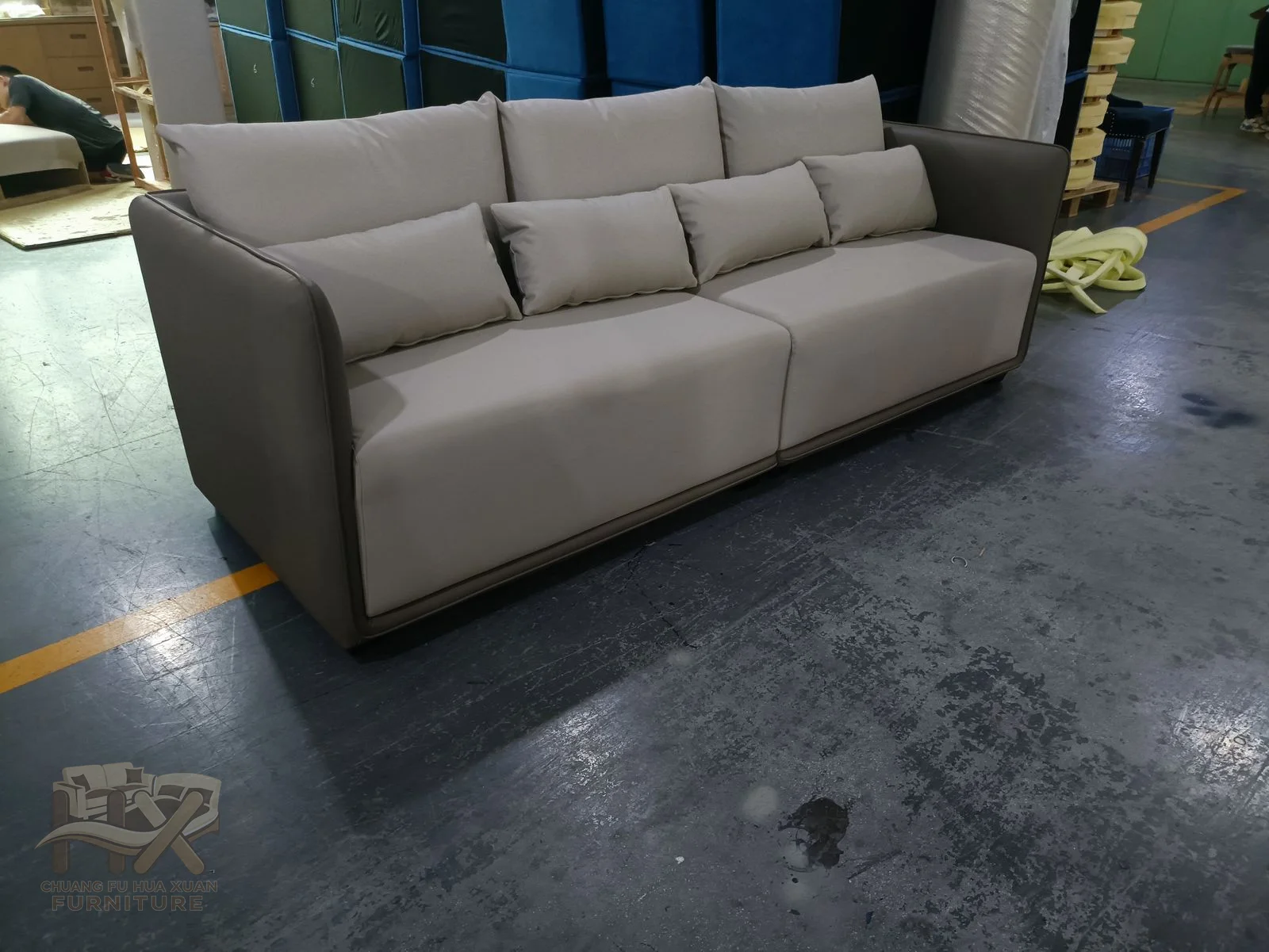 Wide padded arms flank three grey seat cushions and a low straight back on short exposed feet.