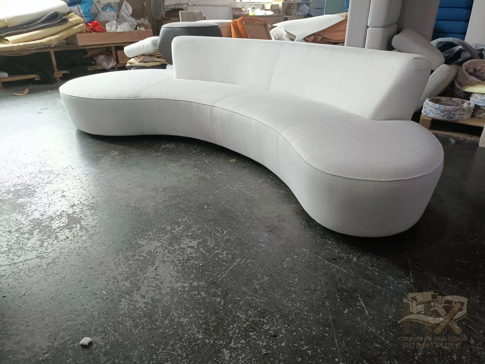A sculptural white seat undulates through several rounded bends, with a low back and no visible legs.