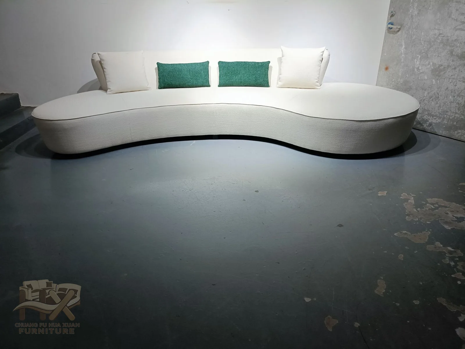 A long white sofa bends into a wave, with a raised end that functions as a curved backrest.