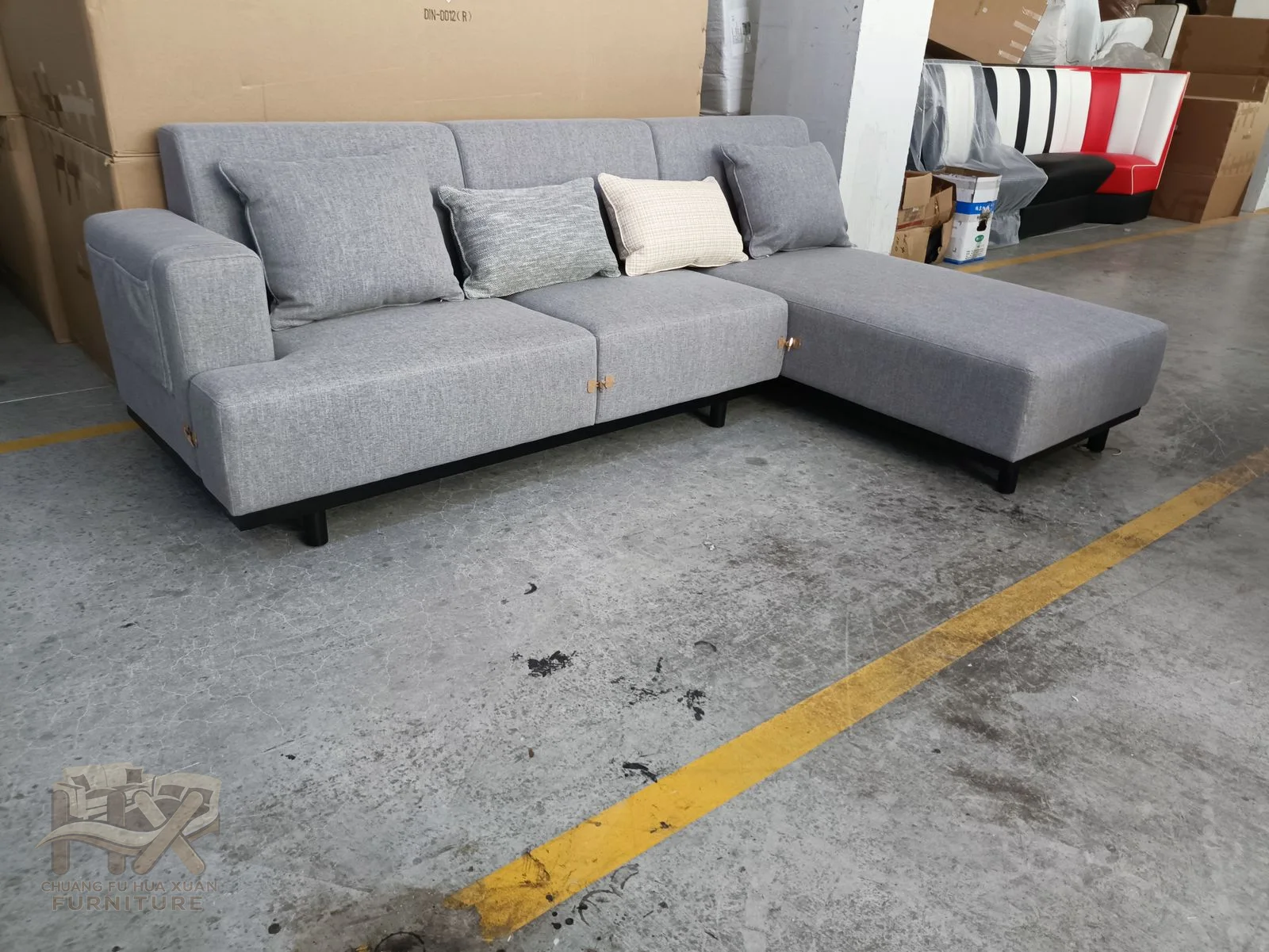 The grey sectional joins a long seat run to a chaise return, with loose cushions inside low straight arms.