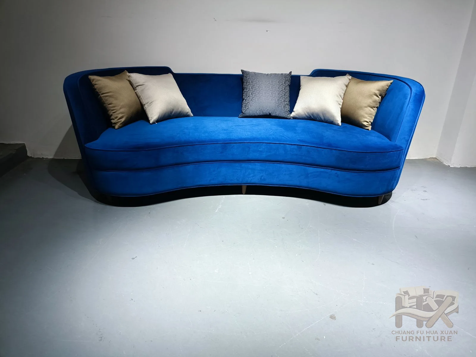 A low blue sofa sweeps upward at each arm, holding pale accent cushions against its curved back.
