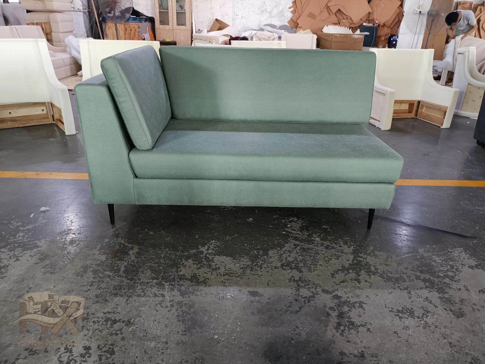 A pale green sofa combines square arms with a low cushioned back and exposed short feet.
