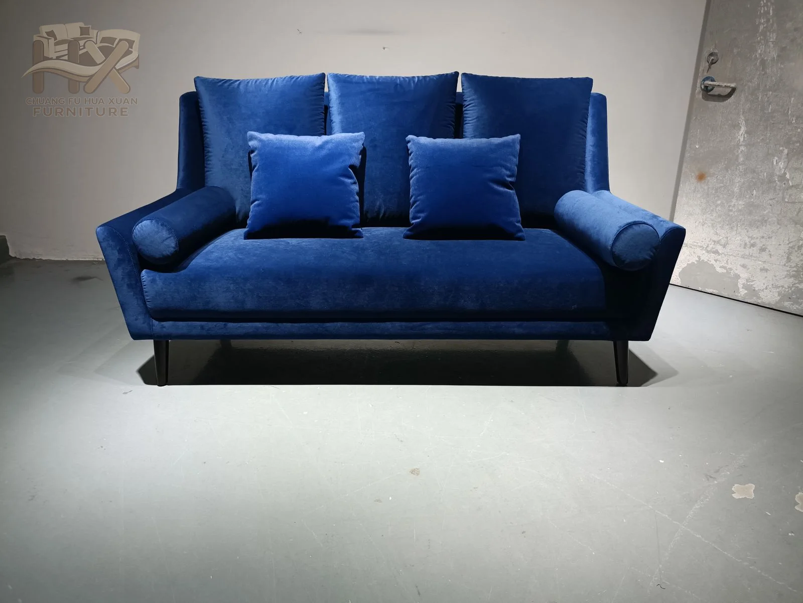 A deep blue two-seat sofa uses firm square arms and closely fitted back cushions over a low base.