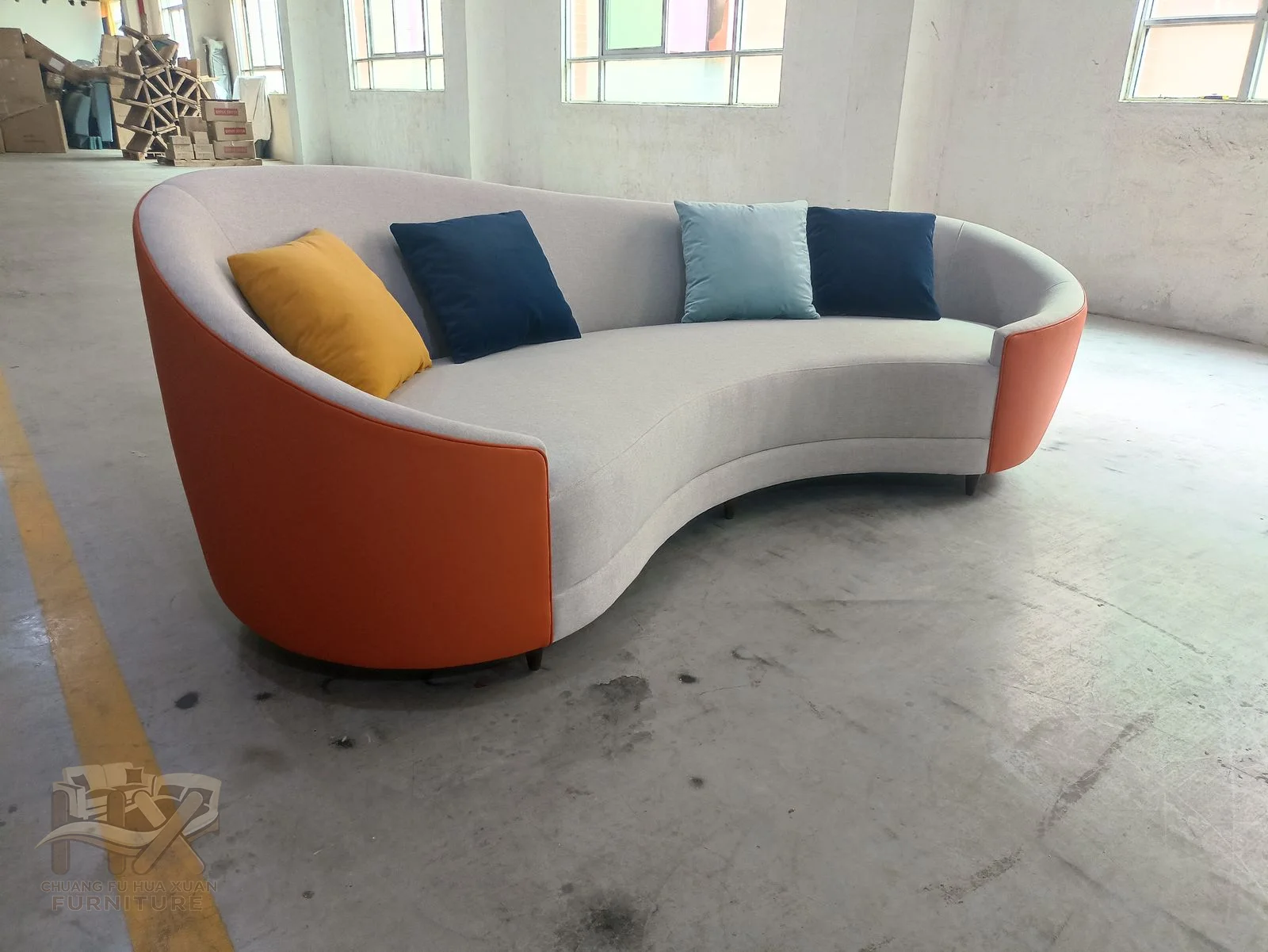Orange outer ends frame a pale curved seat with dark blue and yellow cushions set along the back.
