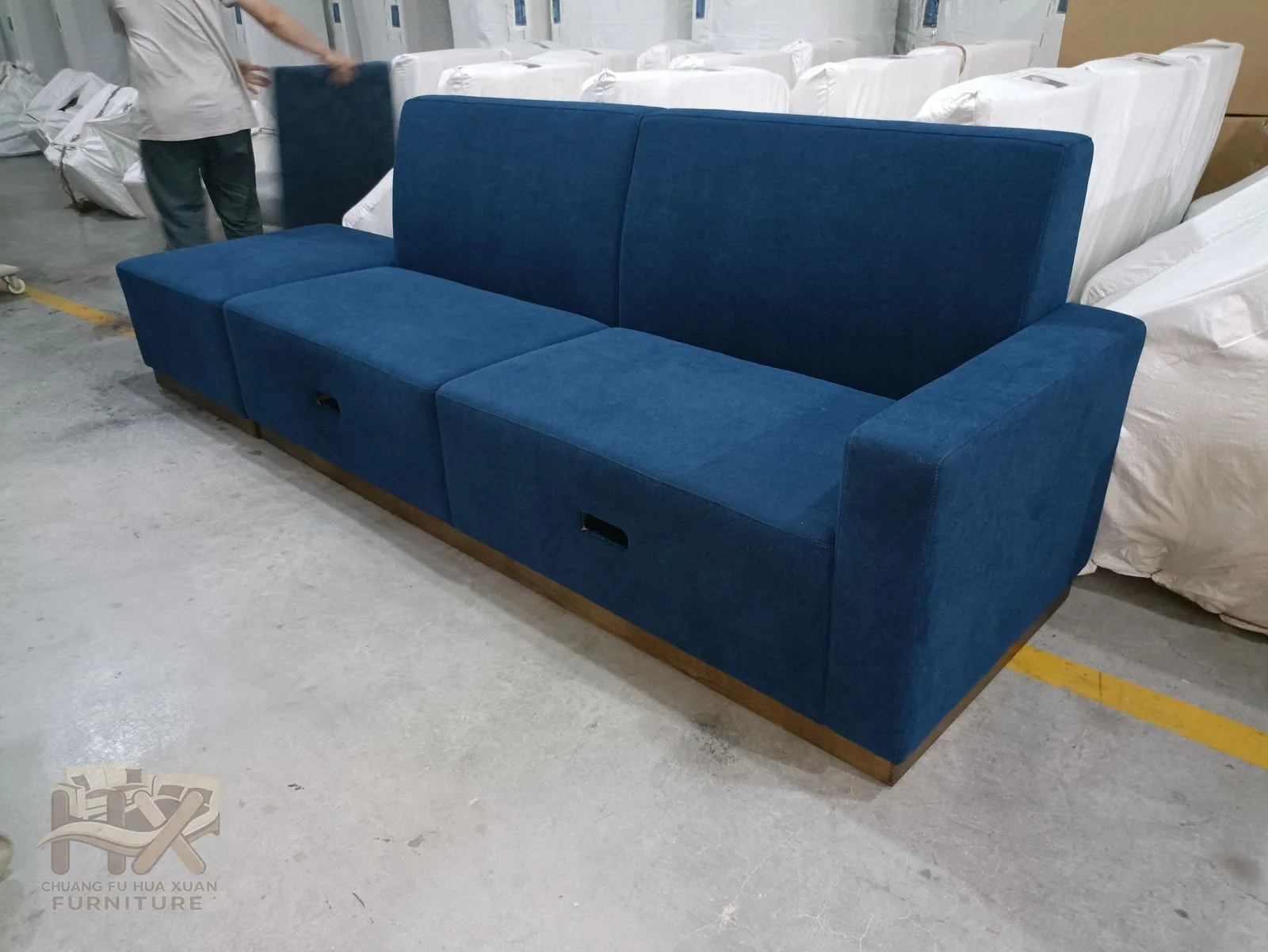 A wide blue seat sits beneath a low straight back between level upholstered arms.