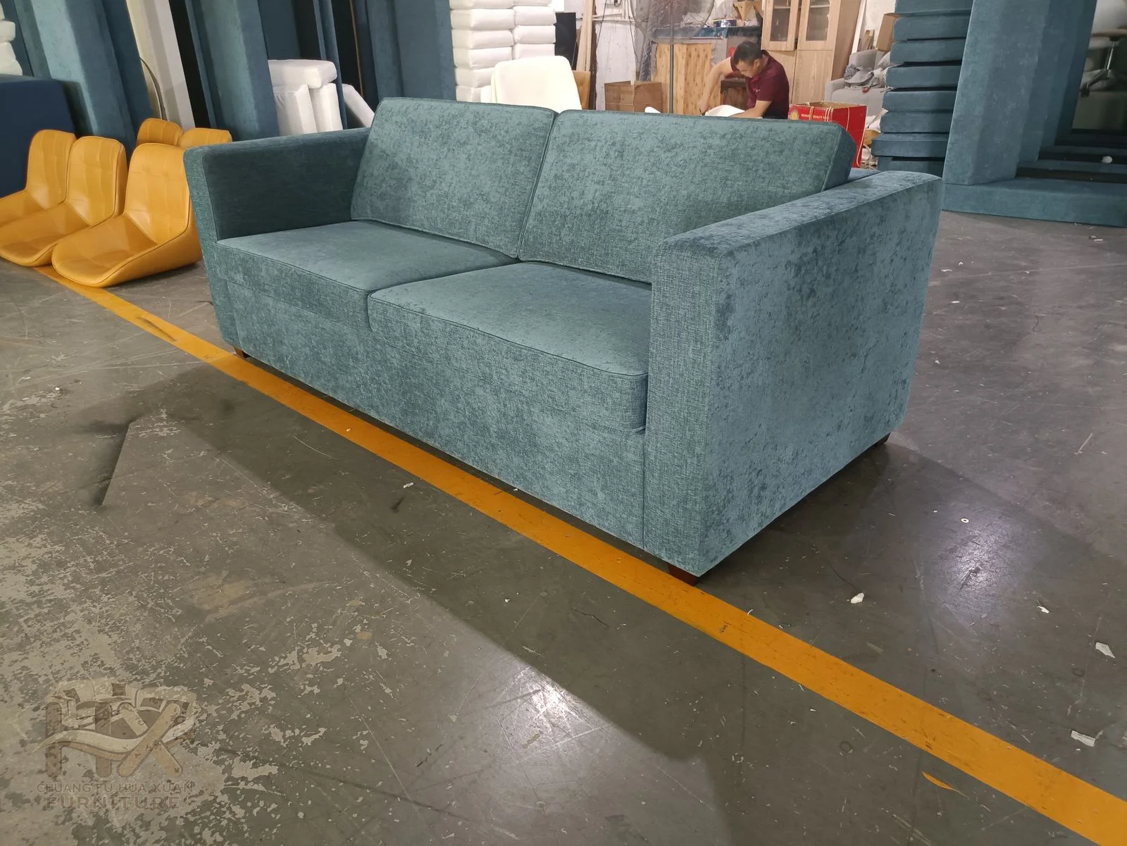 Two blue cushions sit between straight upholstered arms and a low back on small exposed feet.