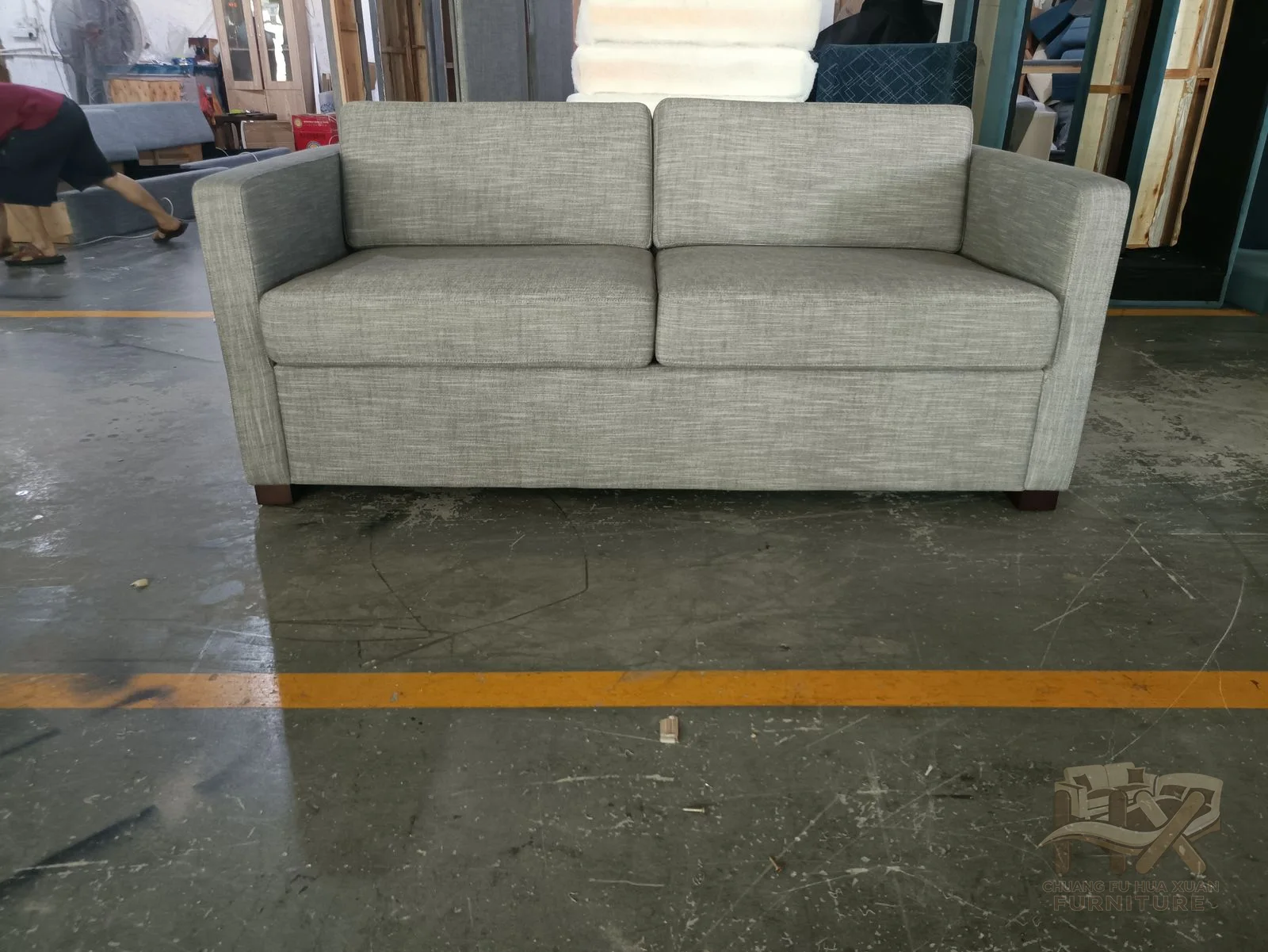 A light grey sofa sets two deep seats between substantial level arms and a low padded back.