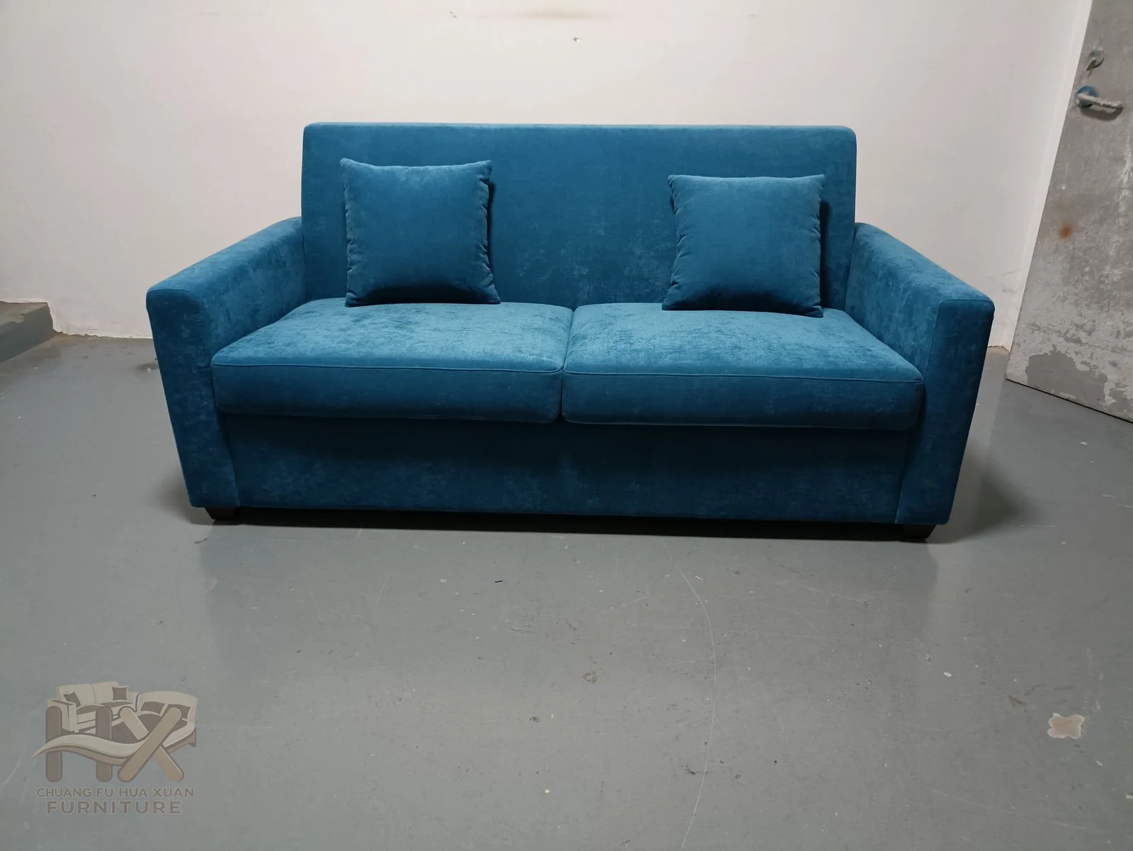 A low blue sofa uses long level arms and two broad loose seat cushions above a compact base.