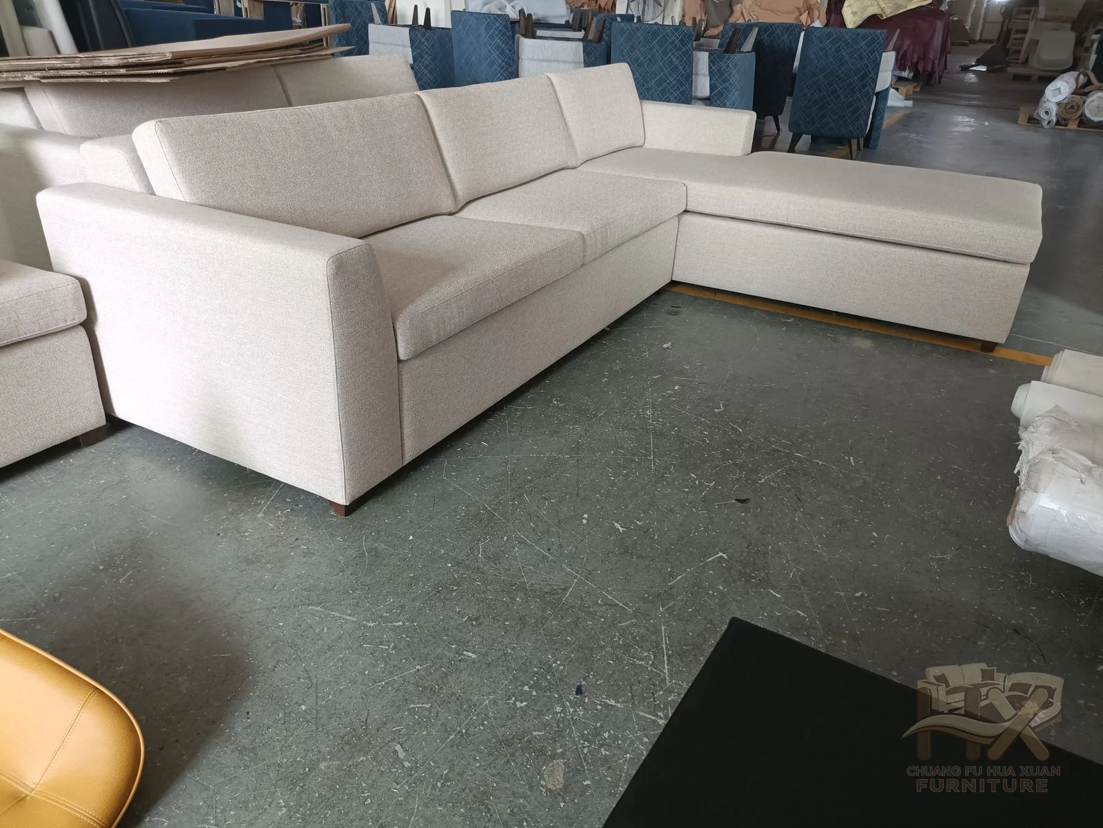 A white sectional combines a straight cushion run with a long chaise return and low arms.