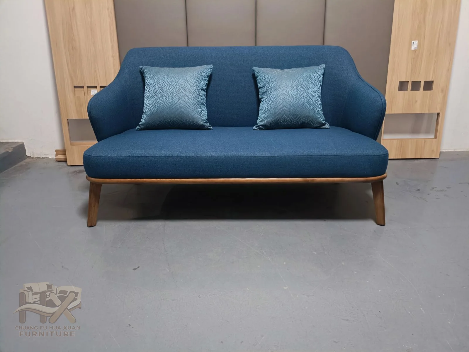 A saturated blue sofa combines a low straight back and broad seat cushions with compact arms.