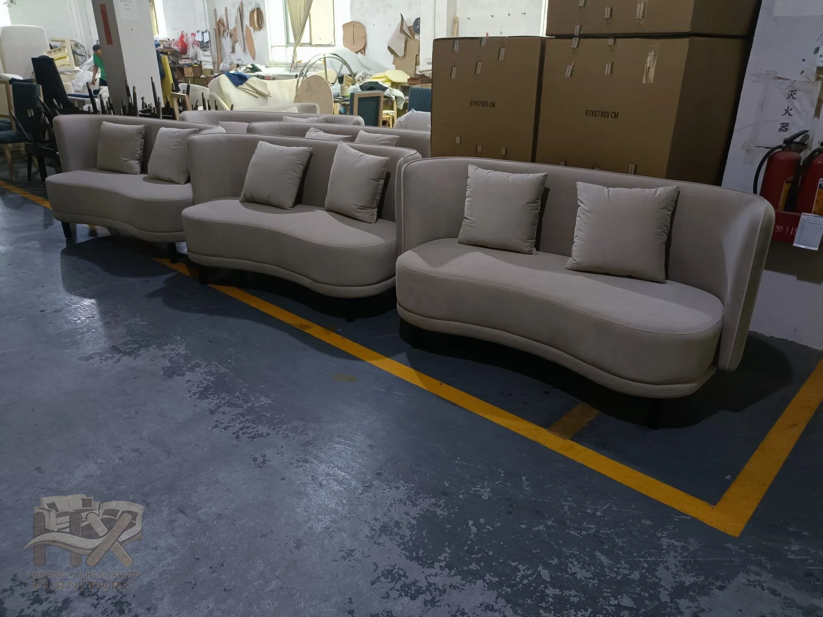 A grey low sofa curves around deep seats beside a matching round ottoman.
