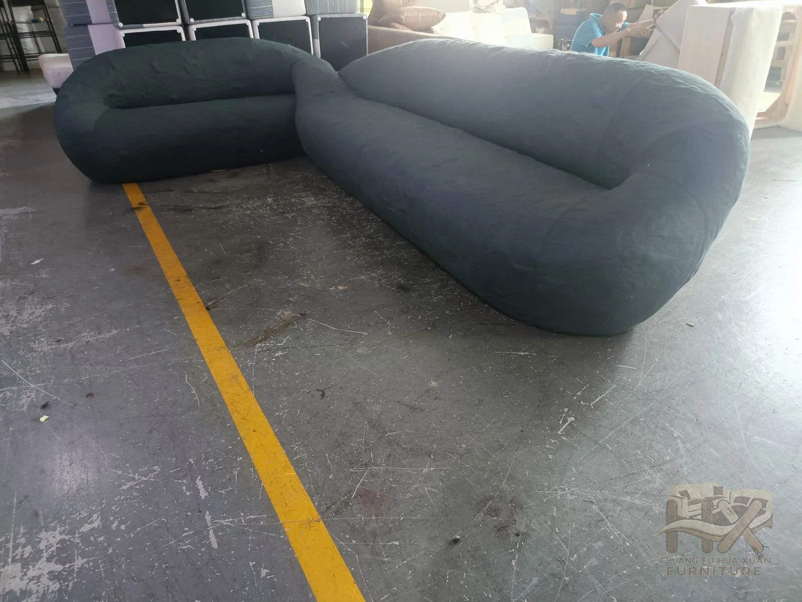 A grey two-seat sofa rounds its low arms and back around a deep continuous seat.