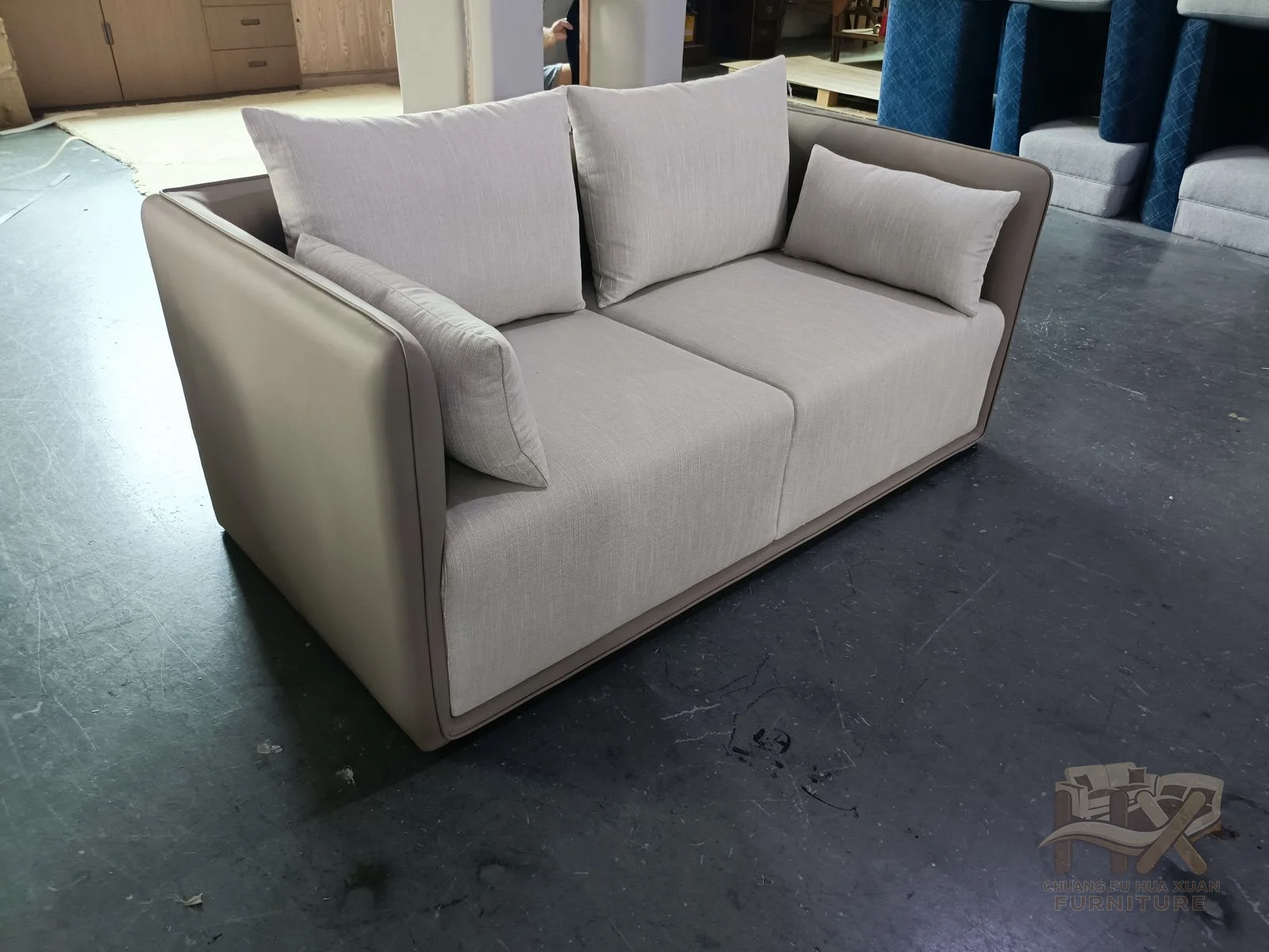 A white sofa holds a regular row of cushions inside straight upholstered arms.