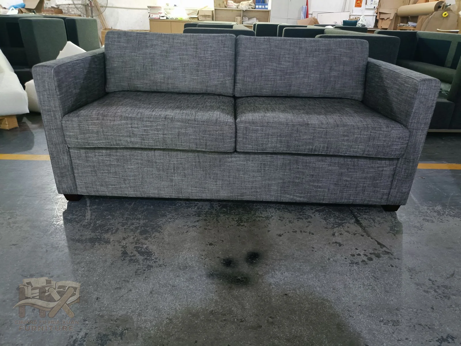 A grey two-seat sofa has low rounded arms and a compact upholstered base.