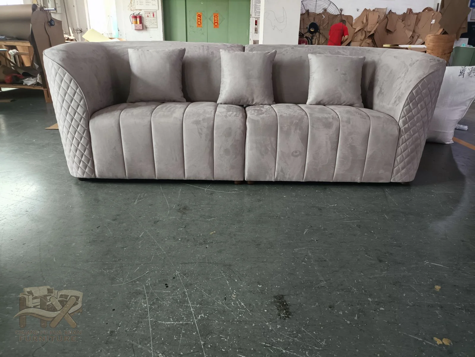 A grey sofa uses repeated vertical channels across its high padded back above straight seats.