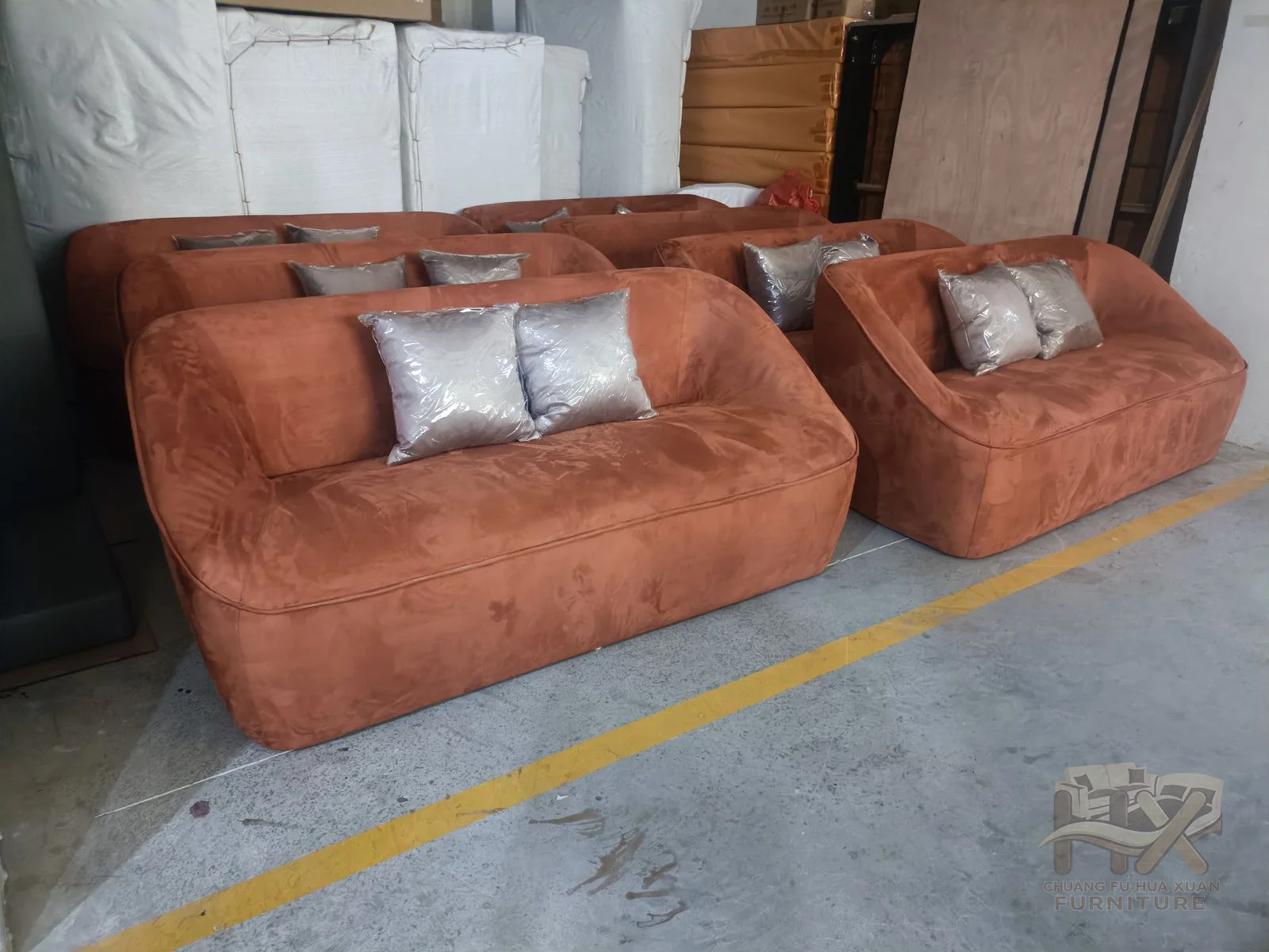 A brown lounge sofa has low square arms and a row of loose back cushions over deep seats.